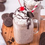 Oreo milkshake with whipped topping, a cherry and a red and white straw