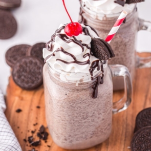 Oreo milkshake with whipped topping, a cherry and a red and white straw